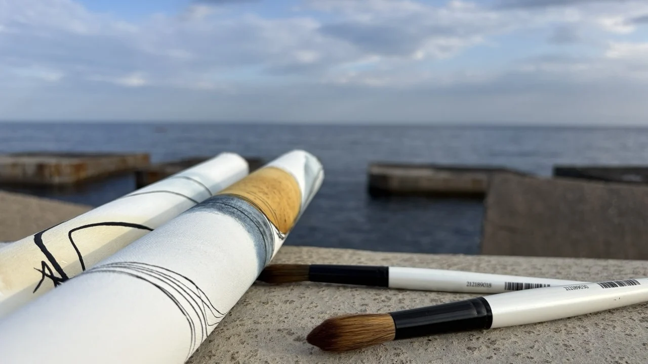 Rolled canvases and brushes by the sea